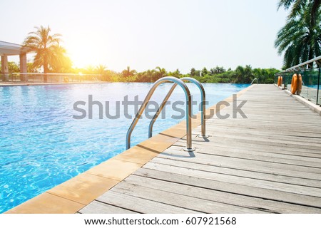 Swimming pool with stair and wooden deck at hotel.