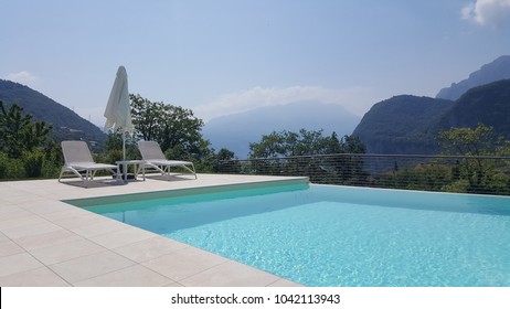 Swimming Pool With Sunbeds And Sun Umbrella And Mountains In The Background