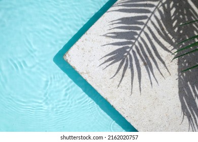 Swimming pool top view background. Water ring and palm shadow on travertine stone - Shutterstock ID 2162020757