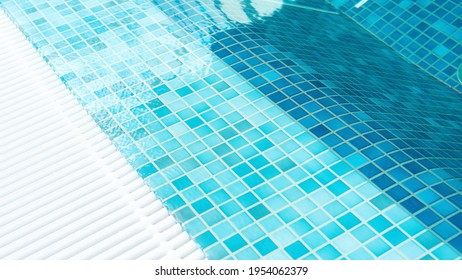Swimming pool top view close-up. Pool water surface background with copy space. Texture of square mosaic blue tiles in a spa wellness center. Drain grids for water in the pool.