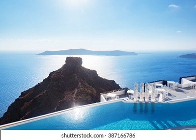 Swimming pool with a view on Caldera over Aegean sea, Santorini, Greece at hot sunny summer day.