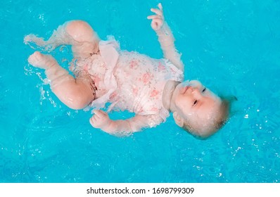 A Swimming Teacher Teaches A Kid To Swim In The Pool