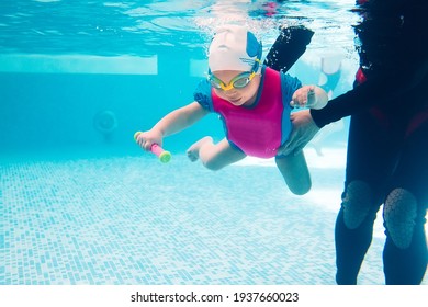 A Swimming Teacher Teaches A Kid To Swim In The Pool