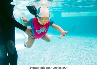 A Swimming Teacher Teaches A Kid To Swim In The Pool