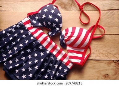 swimsuit in bikini style is striped american flag placed on a wooden background