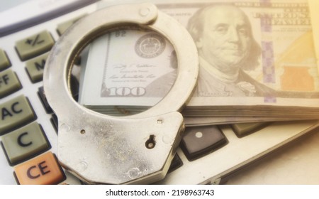 Swindle concept.Police handcuff and banknote on calculator. - Shutterstock ID 2198963743