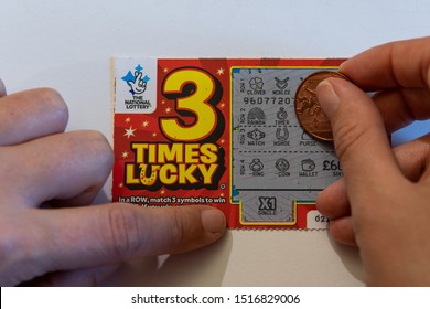 Swindon, England, UK - September 27th, 2019 - Hand Of Woman Holding Coin On Lottery Scratch Card For Cash Prizes To Be Won In British Pounds. Photographed In Swindon, England