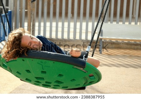 swing for children, boy swinging on a swing, childhood, vacation, weekend, walk along the seashore appy child relaxing in round swing, bare feet, sunny summer day