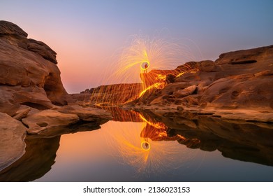 Swing fire dancing show.Swirl Steel Wool light Photography over the rock and water at Sunset SAM PHAN BOK,Ubon ratchathani province,Thailand,ASIA.Photo by long exposure - Powered by Shutterstock