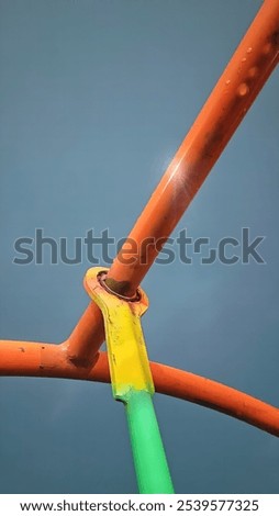 a swing frame that is starting to rust against a dark sky background