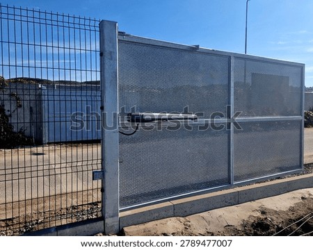 swing gate installed next to wire mesh fence line, featuring automatic linear arm actuator gate opener mounted horizontally across middle rail.Safety Sensor require photo-eye safety beams photocell prevent gate from closing on vehicles or pedestrians