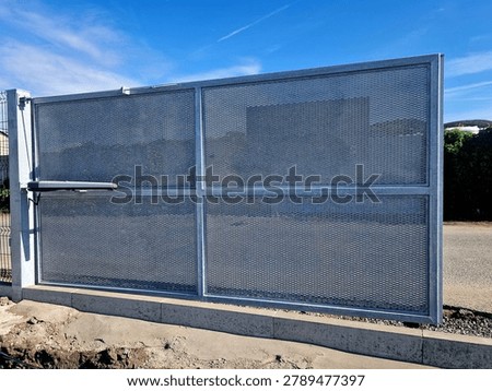 swing gate installed next to wire mesh fence line, featuring automatic linear arm actuator gate opener mounted horizontally across middle rail.Safety Sensor require photo-eye safety beams photocell prevent gate from closing on vehicles or pedestrians