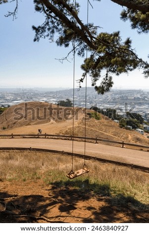 a swing hangs under a tree at the hill of bernal heights with a beautiful view over San Francisco at sunrise, California