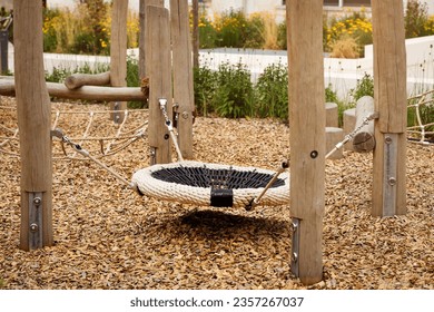 Swing Nest of Modern Children Playground with Robinia Timber and Wood Chips Groung Cover Floor. Modern Play Equipment from Wood Lumber and Natural Wooden Covering