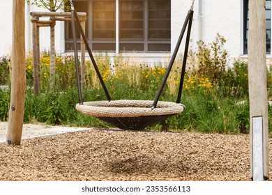 Swing in Playground Yard. Modern Swing Nest with Wood Chip Covering Floor and Robinia Timber in Play Area.