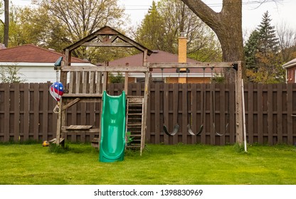 Swing Set In Backyard During Spring Season With Lush Grassy Lawn