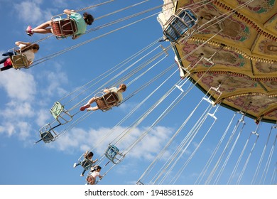 Swinging chairs on ride against blue sky
