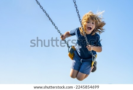 Swinging on playground. Funny kid on swing. Little boy swinging on playground. Happy cute excited child on swing. Cute child swinging on a swing. Crazy playful child swinging very high.