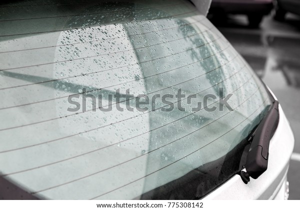 The swirling\
rear window of the car covered with drops of water after the rain,\
heated rear window and car\
wiper.