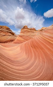Swirling sandstone waves and rolling clouds at "The Wave" - a dramatic and colorful erosional sandstone rock formation in North Coyote Buttes area at Arizona-Utah border. 