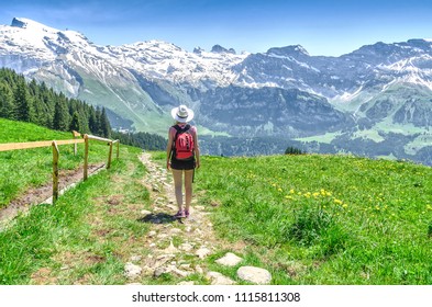 Swiss Alps. A Girl In A Hat Walking Down A Mountain Path Down. Engelberg Resort
