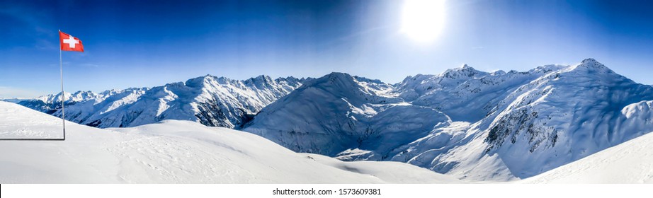 swiss alps mountain panorama in winter snow with the swiss flag on a sunny day with blue sky in the ski area gstaad