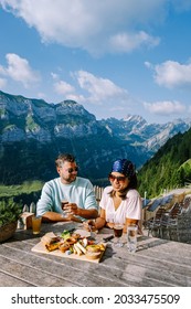 Swiss Alps and a mountain restaurant under the Aescher cliff viewed from mountain Ebenalp in the Appenzell region in Switzerland Aescher cliff Swiss, couple man and woman mid age visiting Switzerland