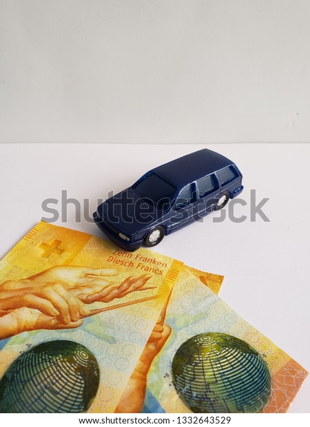 swiss\
banknotes and figure of a car in dark\
blue