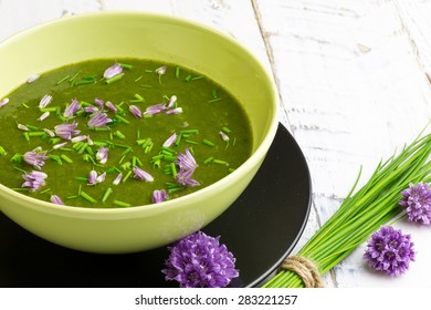 Swiss Chard And Potato Cream Soup With Chopped Chives With Edible Chives Flowers In Green Ceramic Bowl