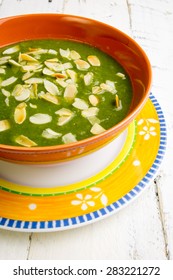 Swiss Chard And Potato Cream Soup With Chopped Roasted Almonds In Brown Ceramic Bowl