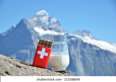 Swiss chocolate and jug of milk against mountain peak. Switzerland