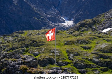 Swiss flag waving at Swiss mountain Pass Susten with Tschingelfirn glacier in the background on a sunny summer day. Photo taken July 13th, 2022, Susten Pass, Switzerland. - Shutterstock ID 2187797283