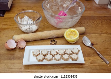 Swiss Or German Style Cinnamon Star Shaped Christmas Cookies Known As Zimtsterne With Some Of The Ingredients On Messy Kitchen Bench - Lemons, Eggs,