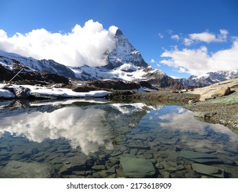 Swiss Matterhorn Reflected In A Small Lake. Scenic View With Clouds On One Side Of The Mountain And No People Visible.