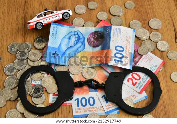 swiss money banknotes and coins with handcuff and police
car 