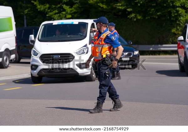 Swiss police man managing traffic at first\
stage of bicycle race Tour de Suisse on a sunny summer day. Photo\
taken June 12th, 2022, Forch,\
Switzerland.