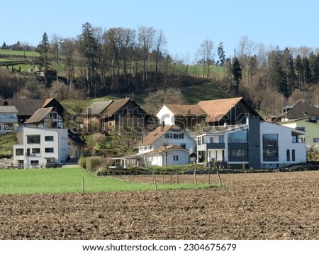 Similar – A tractor turns mown hay in a field in a small community