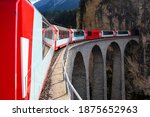 Swiss Train Bridge in Grisons Landscape with famous Landwasser Viaduct and Tunnel is a world heritage railway line in the alps crossed by a regional train but also the Glacier or Bernina Express