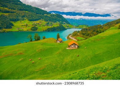 Swiss village Lungern with its traditional houses and old church tower Alter Kirchturm along the lake Lungerersee, canton of Obwalden, Switzerland