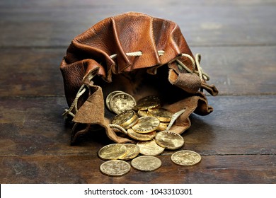 Swiss Vreneli gold coins in a leather purse on rustic wooden background