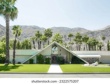 Swiss-Miss Style Midcentury Modern House in Palm Springs, California with palm trees and mountains in the background on a sunny day.