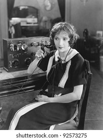 Switchboard operator sitting at telephone switchboard and talking