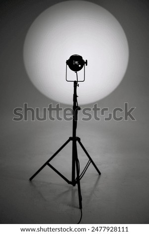 Switched-on source of constant light shines on white cyclorama. Tripod, light diffuser and other equipment for photostudio. A professional pulsed light source. Organization of photoshoots for brands