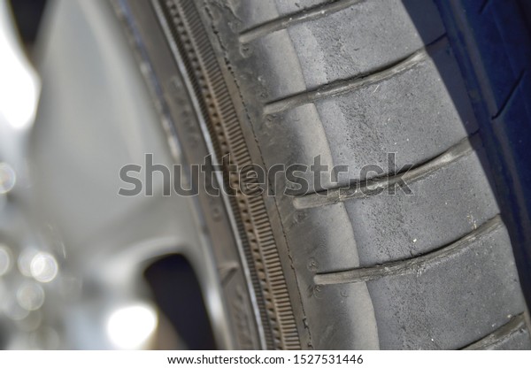 Switzerland, August 2019. Highway to Germany, at a\
parking area a parked car has tires with tread marked by wear and\
summer heat.