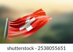 Switzerland flag waving with beautiful background. The flag blowing with green blur background. Switzerland national flag for independence day.