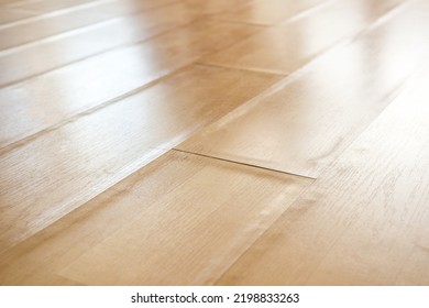 Swollen laminate flooring from flood or water damage, perspective view. Close up of light beige buckling laminate boards with bent edge pieces. Floor damage texture. Selective focus in center. - Shutterstock ID 2198833263