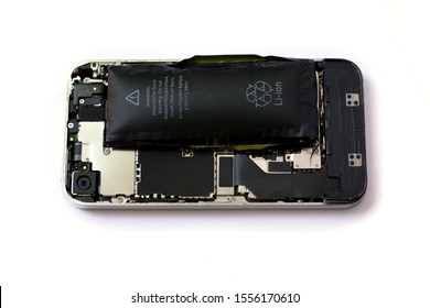 Swollen lithium ion polymer battery inside a mobile phone on white background isolated
