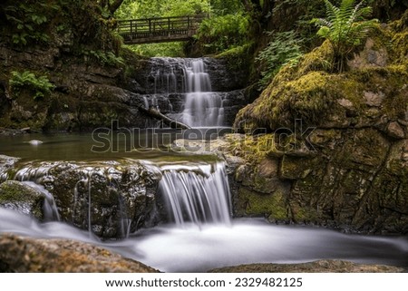 The Sychryd Cascades or Sgydau Sychryd Falls with wooden bridge in the Waterfall Country near the Dinas Rock, Pontneddfechan, Brecon Beacons National Park, South Wales, UK. Long exposure water.