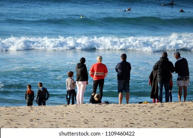 Sydney, AU - MAY 20, 2018: Crowd Of People Standing On The Sandy Beach, Looking For Blurred Windsurf Players On The Wave Sea.