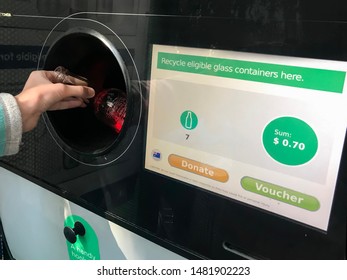 Sydney / Australia 08-16-2019. Return And Earn Public Return Point For Recycling. Reverse Vending Machine For Refund & Recycling Of Glass Bottles. Hand Holding A Bottle.  